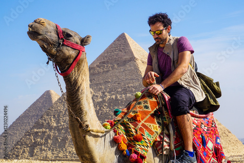 Nomadic Travel Experience in Giza Egypt with a Man Riding a Camel in Front of the Legendary Pyramids in a Vast Desert