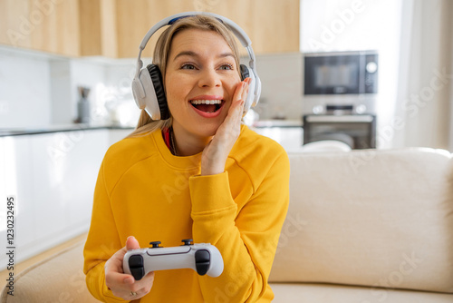 Joyful woman enjoying console gaming with headphones in a cozy home setting