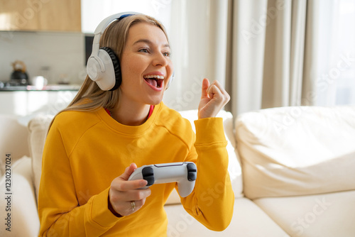 Joyful woman wears headset and plays video games in a bright living room