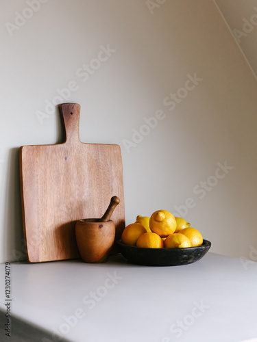 Bowl of lemons and a cutting board on a kitchen counter.