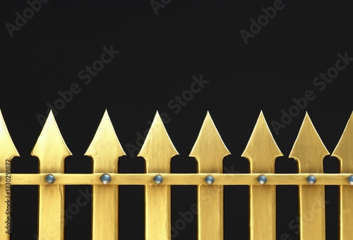 Ornate gold metal fence with sharp spearheads on a black background. Rustic wrought iron fence design element. Detail of pointed golden iron gates isolated on a black background. Copy space. photo