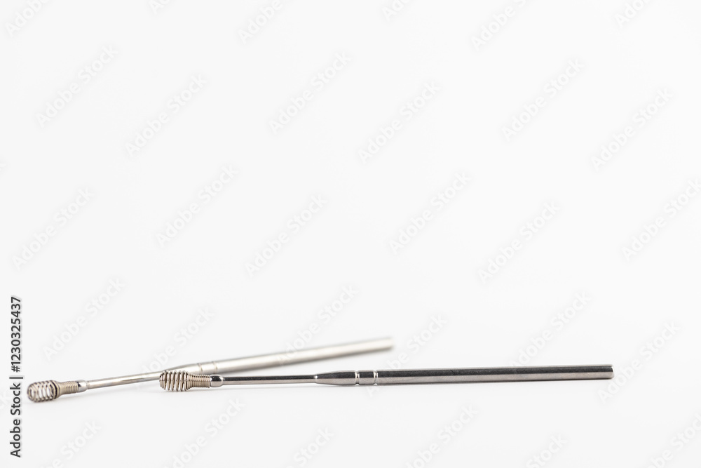 On a white background lie iron modern ear sticks with a spiral for removing dirt from the ear opening prevention of ear diseases home use stainless steel On a white background lie iron modern ear sticks with a spiral for removing dirt from the ear opening prevention of ear diseases home use stainless steel