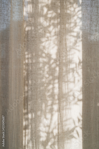 Floral sunlight shadows on a neutral beige linen curtains, aesthetic minimalist natural background with copy space
