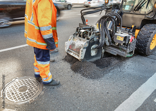Workers repair the street with heavy machinery on a bustling city road during daylight hours. Copy space.