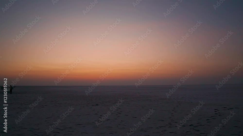 Orange clouds above the salt flats of the Rann of Kutch just before sunrise as seen on the way to Dholavira in Kutch, Gujarat, India. Beautiful sunrise background in the desert with copy space. Orange clouds above the salt flats of the Rann of Kutch just before sunrise as seen on the way to Dholavira in Kutch, Gujarat, India. Beautiful sunrise background in the desert with copy space.
