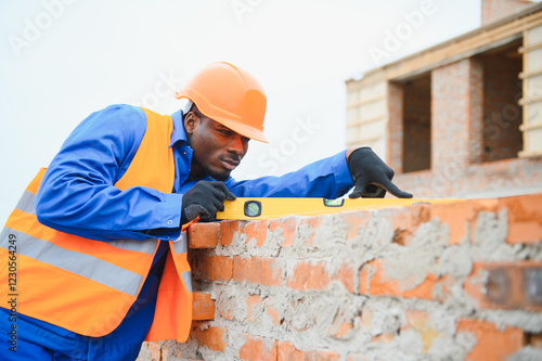 Bild auf Leinwand Builder in workwear and protective helmet keeping level handtool on surgace of b