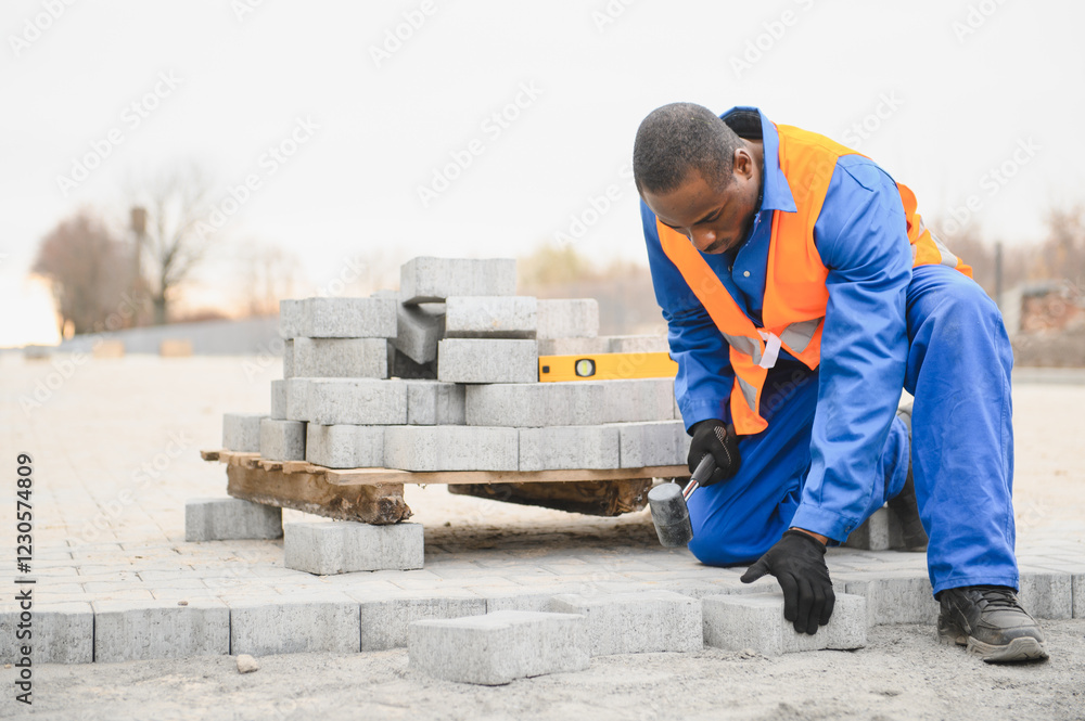 An African American worker lays pavers in a yard or sidewalk An African American worker lays pavers in a yard or sidewalk