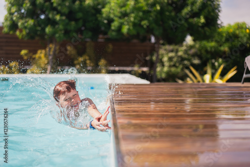 Child splashing happily in a sunlit outdoor pool with greenery photo