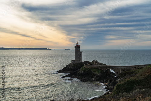 Le phare du Petit Minou, dressé face à l’Atlantique, baigné par une lumière hivernale tamisée sous un ciel voilé aux nuances douces de bleu, gris et jaune. photo