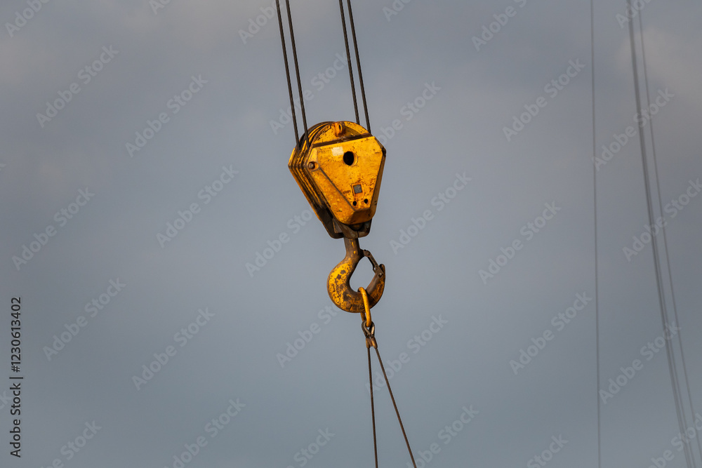 A yellow crane hook is suspended in the air A yellow crane hook is suspended in the air