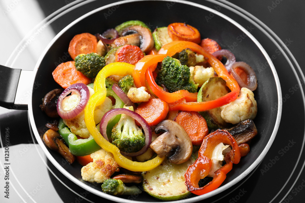 Frying pan with mix of vegetables and mushrooms on cooktop, closeup Frying pan with mix of vegetables and mushrooms on cooktop, closeup