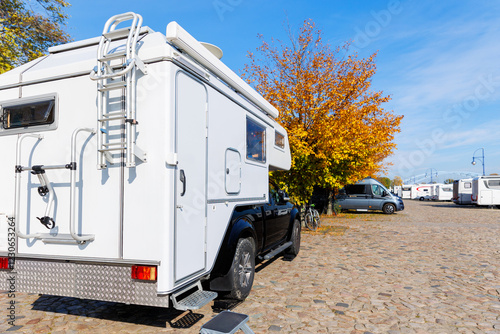 Back view pick-up off-road expedition truck parked many modern campervan recreational motor home vehicle camper park site Magdeburg city. Motorhome campground station travel destination. RV lifestyle