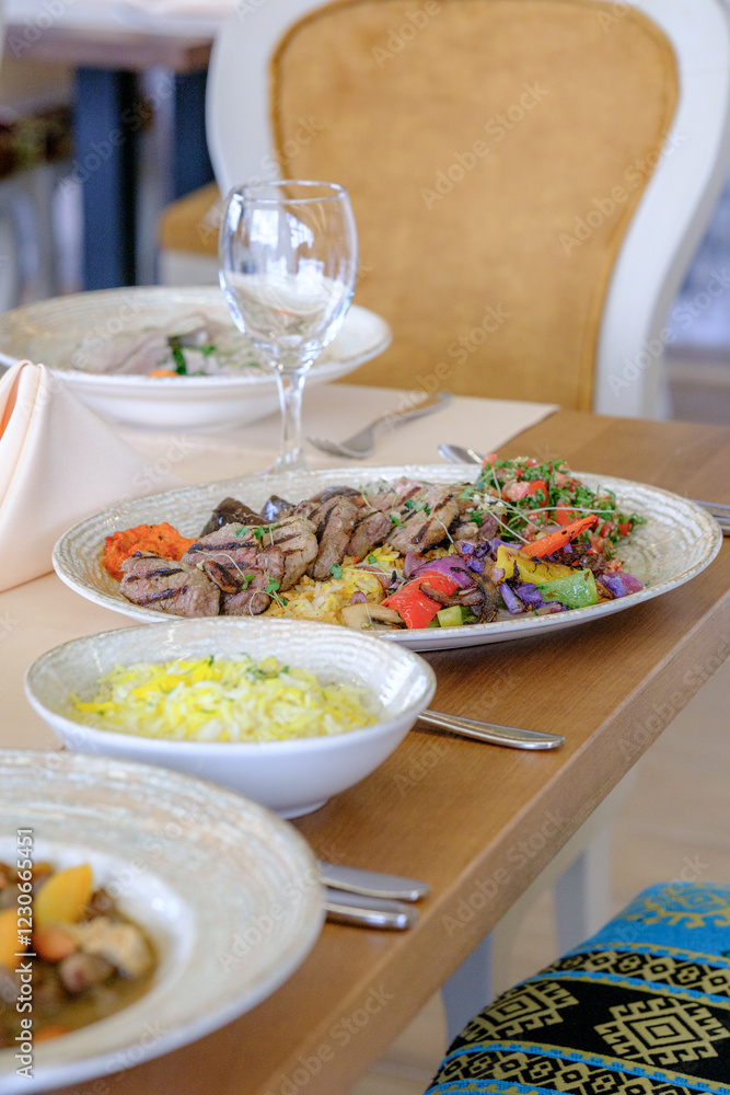 Grilled meat with colorful vegetables and rice served on elegant plates at a restaurant table Grilled meat with colorful vegetables and rice served on elegant plates at a restaurant table