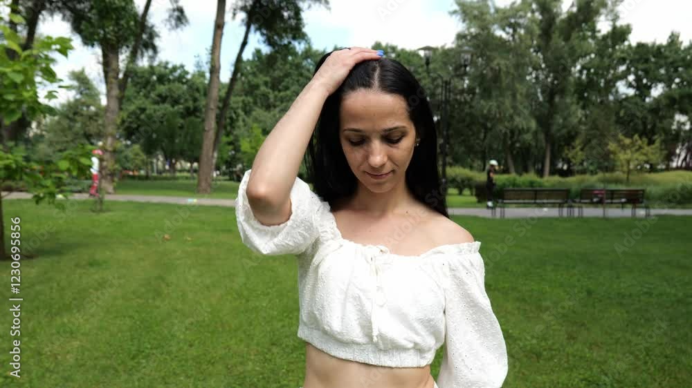 Portrait of a beautiful young brunette woman in a white dress walking forward in a beautiful summer city park. Long hair female. Slow motion portrait Portrait of a beautiful young brunette woman in a white dress walking forward in a beautiful summer city park. Long hair female. Slow motion portrait