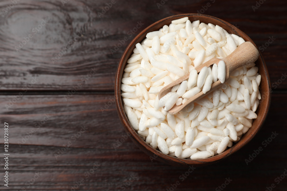 Puffed rice in bowl and scoop on wooden table, top view. Space for text