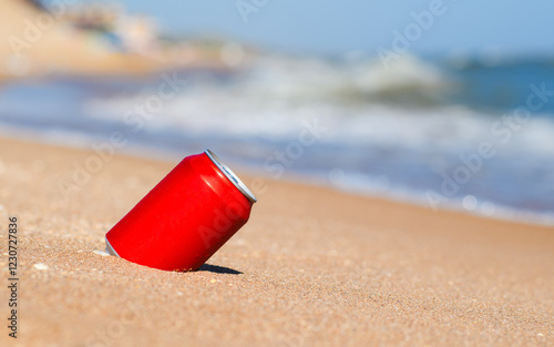 Cold drink can on the beach. Red aluminum can in the sand. Summer vacation concept photo