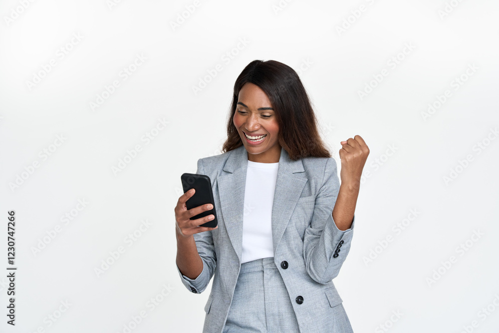 Excited young African American business woman wearing suit using cell phone feeling winner isolated on white. Happy businesswoman with yes gesture looking at smartphone winning profit in mobile app. Excited young African American business woman wearing suit using cell phone feeling winner isolated on white. Happy businesswoman with yes gesture looking at smartphone winning profit in mobile app.