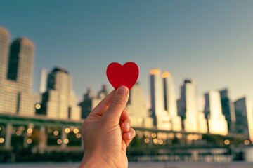 hand holding heart on New York city background showing love charity support compassion, helping friend in need, Valentine's Day concept