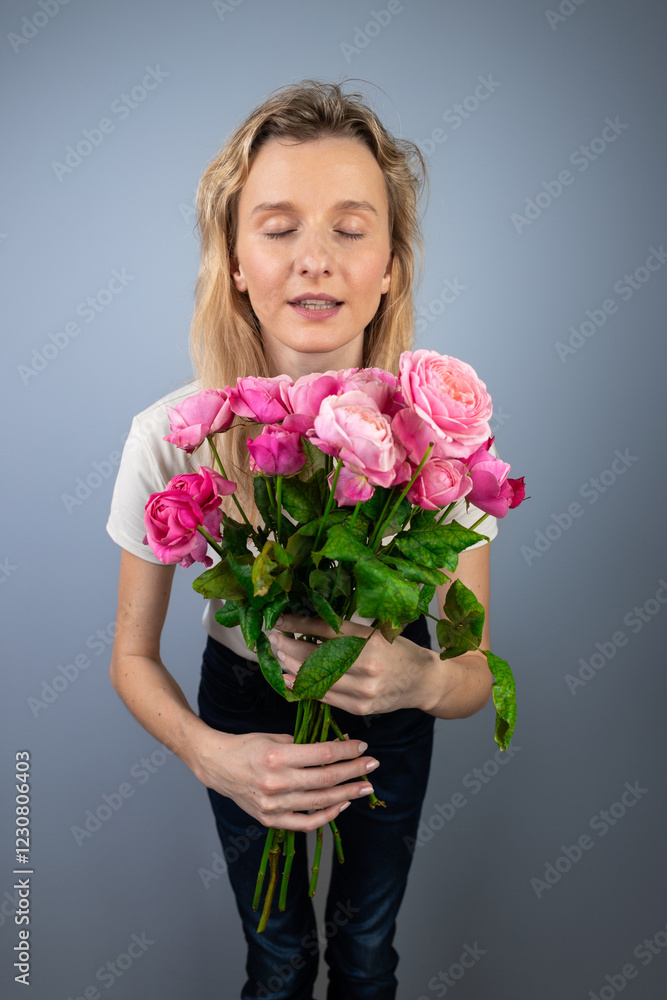 on a light gray background a young blonde girl with a large bouquet of pink peony roses women's holiday March 8 first date emotions on the face smiling girl open mouth on a light gray background a young blonde girl with a large bouquet of pink peony roses women's holiday March 8 first date emotions on the face smiling girl open mouth
