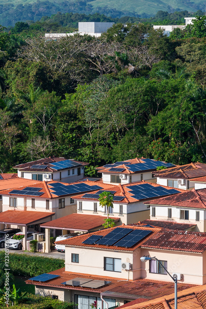 Obraz premium A suburban neighborhood with terracotta-roofed houses featuring solar panels, surrounded by lush greenery. A sustainable community embracing clean energy and eco-friendly living