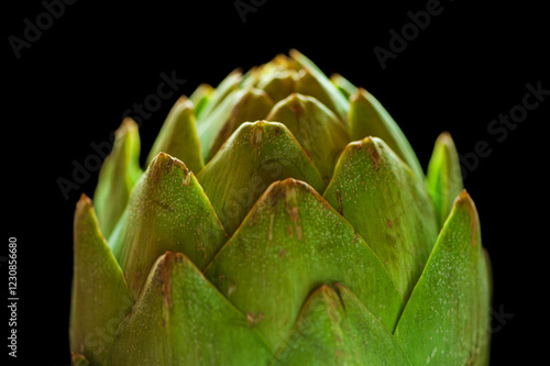 Closeup shot of the top of a raw artichoke against a black background