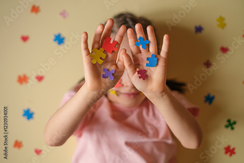 A child hides face behind his hands with colorful puzzles - the emblem of autism. Mental and developmental disorders in people with autism spectrum disorder