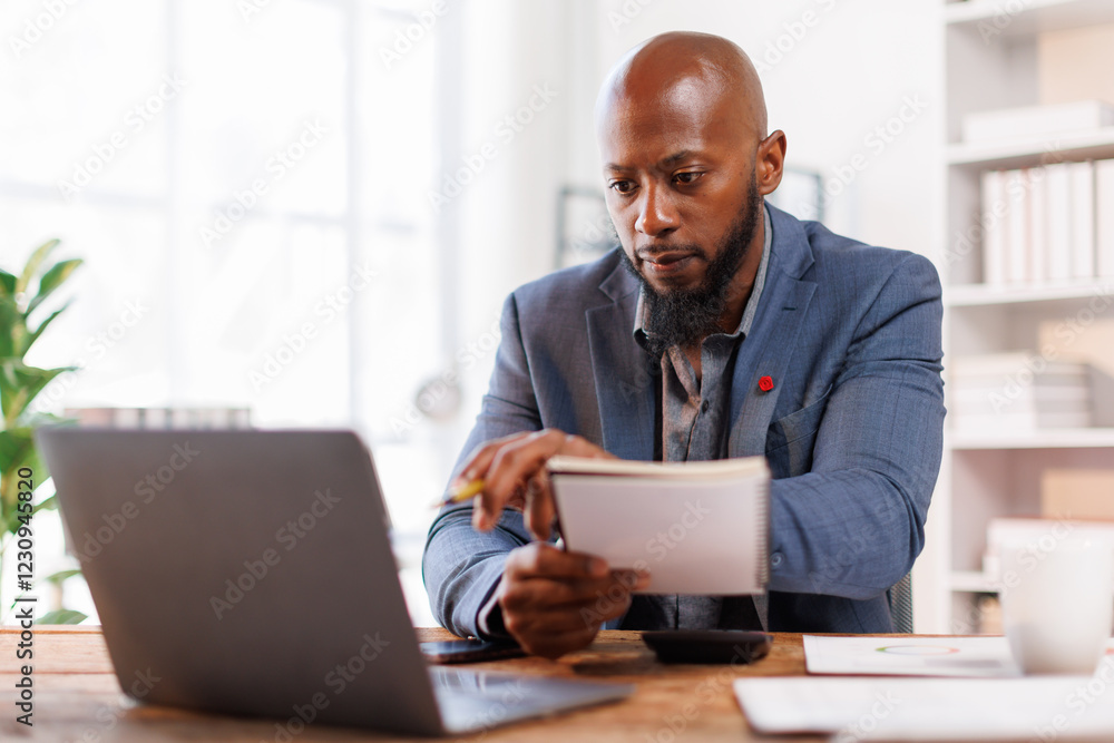An office scene showing a professional at his desk, using a laptop for various business activities and strategies.African American Businessman work. An office scene showing a professional at his desk, using a laptop for various business activities and strategies.African American Businessman work.