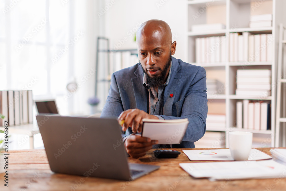 An office scene showing a professional at his desk, using a laptop for various business activities and strategies.African American Businessman work. An office scene showing a professional at his desk, using a laptop for various business activities and strategies.African American Businessman work.