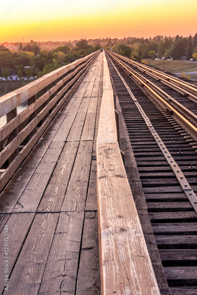 Fototapeta premium A wooden bridge spans a river with a train track running along the side