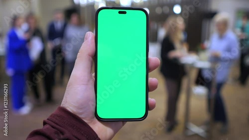 Wallpaper Mural Person is holding a green phone in a room with people. Scene is casual and relaxed Torontodigital.ca