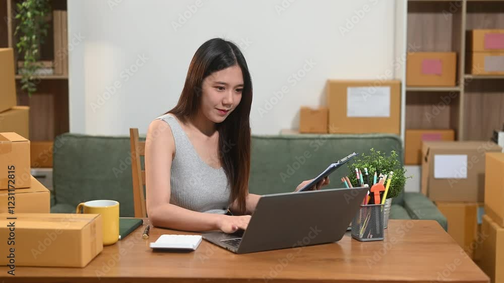 Young business owner woman prepare parcel box and standing check online orders for deliver to customer Young business owner woman prepare parcel box and standing check online orders for deliver to customer