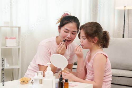 Photography Happiness of Caucasian daughter and Asian mother as they apply lipstick together