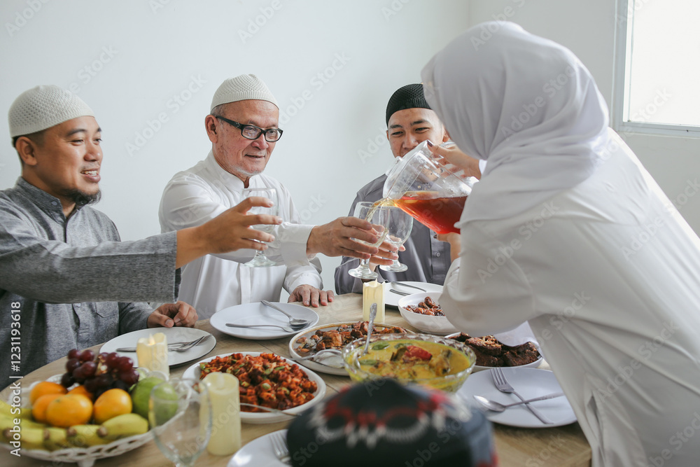 Young Muslim Woman Pouring Tea Into The Glass During Eid Celebration At Dining Room Young Muslim Woman Pouring Tea Into The Glass During Eid Celebration At Dining Room