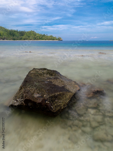 beach rocks with a background of blue sea and clean white sand photo