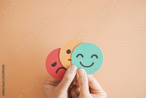 Hands holding sad face hiding behind happy face, bipolar and depression, mental health, split personality, mood change concept