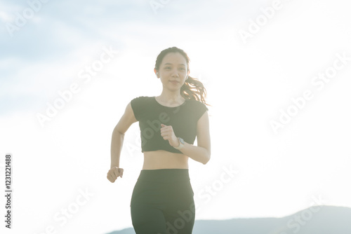 A woman in sportswear running in the park, enjoying fresh air, engaging in outdoor activities to maintain a healthy lifestyle, boosting cardiovascular health, and feeling happy and energetic photo