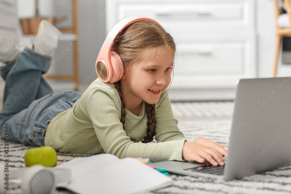 Little girl in headphones with laptop studying computer sciences online at home Little girl in headphones with laptop studying computer sciences online at home