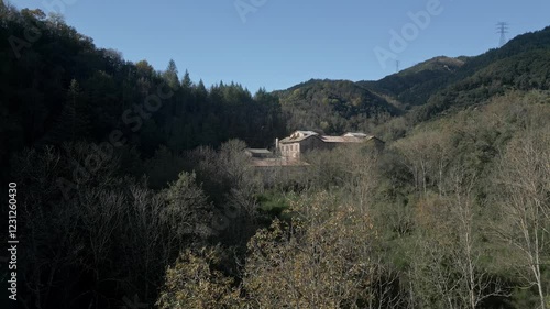 Sunlight illuminates the sant hilari sacalm thermal baths museum, nestled in a valley amidst autumnal foliage and rolling hills in girona, catalonia photo