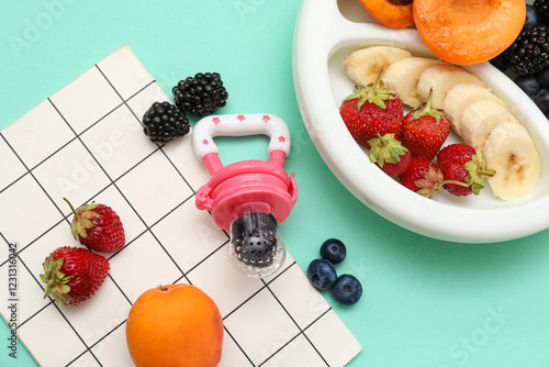 Composition with baby nibbler, ripe fruits and notebook on color background photo