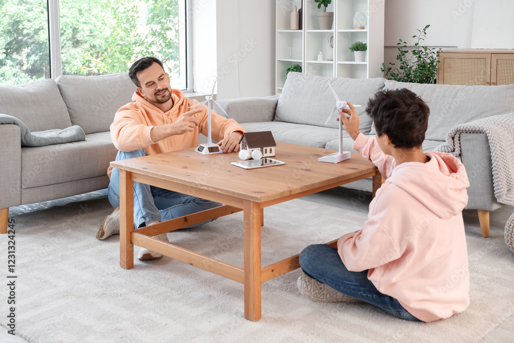 Teenage boy and his father with wind turbine models on table at home Teenage boy and his father with wind turbine models on table at home