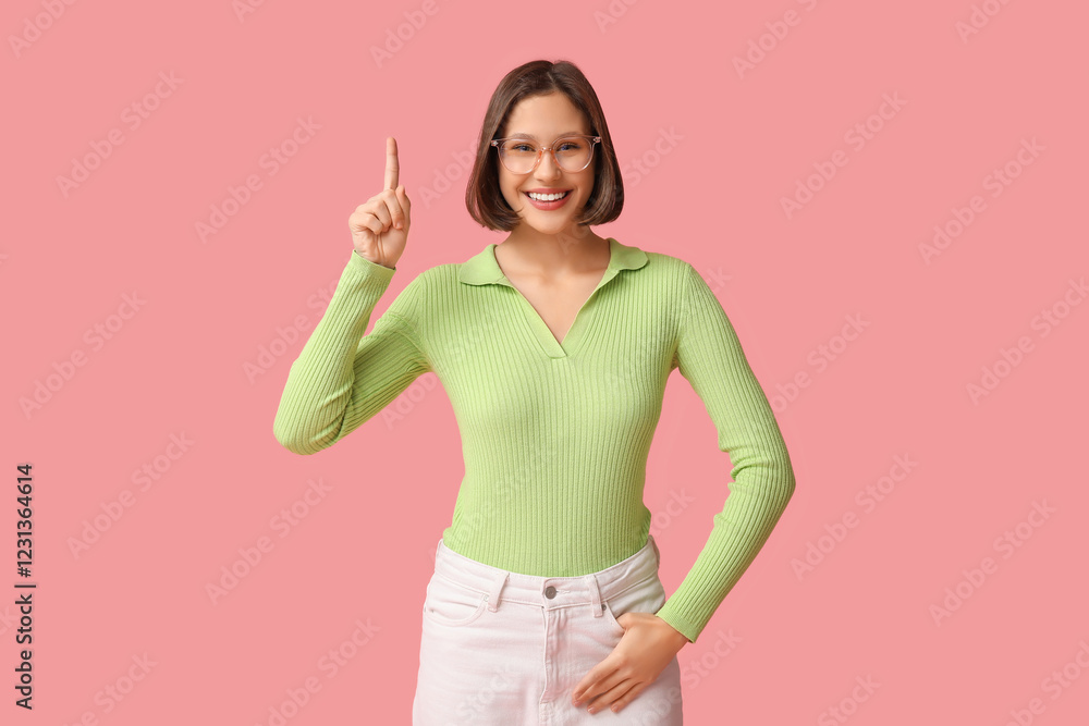 Beautiful young woman pointing at something on pink background Beautiful young woman pointing at something on pink background