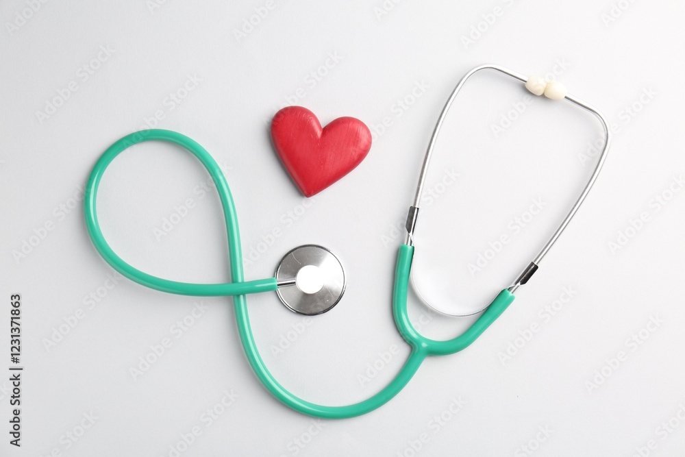 Cardiology. Stethoscope and red decorative heart on white background, flat lay Cardiology. Stethoscope and red decorative heart on white background, flat lay