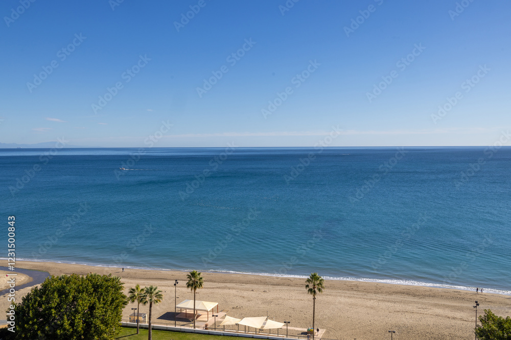 Photo of the beautiful beach front in the town of Fuengirola Mijas in Spains Costa Del Sol showing the sandy beach front and palm trees on a sunny day