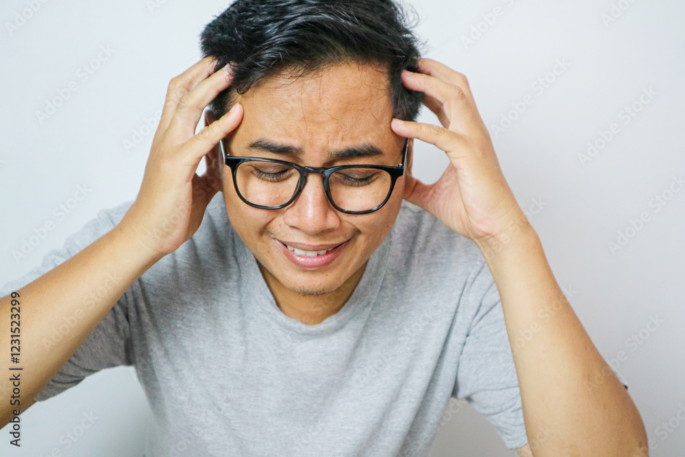 Stressed man sitting on sofa holding his head, feeling overwhelmed and anxious. Man experiencing mental health issues, worry, frustration, and emotional stress. Concept of anxiety and mental health Stressed man sitting on sofa holding his head, feeling overwhelmed and anxious. Man experiencing mental health issues, worry, frustration, and emotional stress. Concept of anxiety and mental health