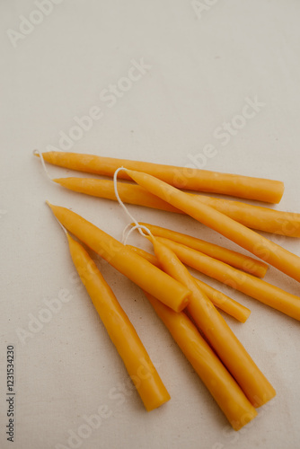 Handmade beeswax candles lie on a light fabric background