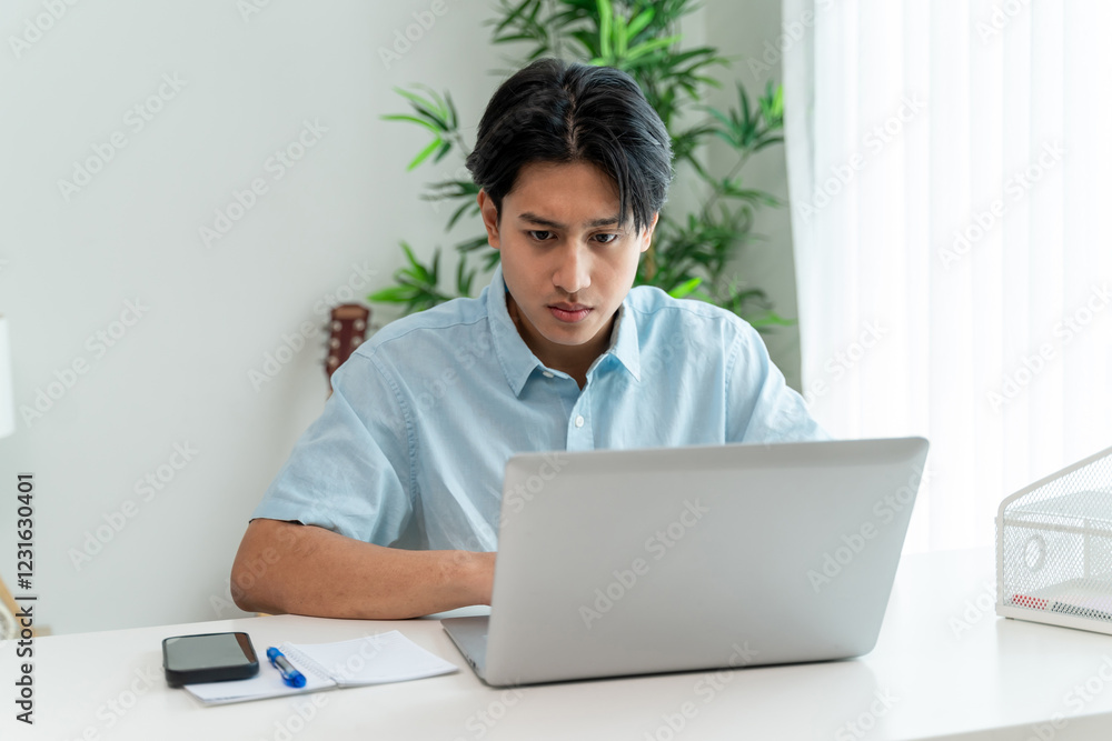 Asian young businessman typing on computer while working from home. Asian young businessman typing on computer while working from home.