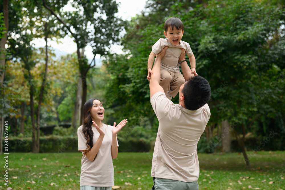 Obraz premium Happy father lifting his little son into the air enjoys spending leisure time together at outdoor