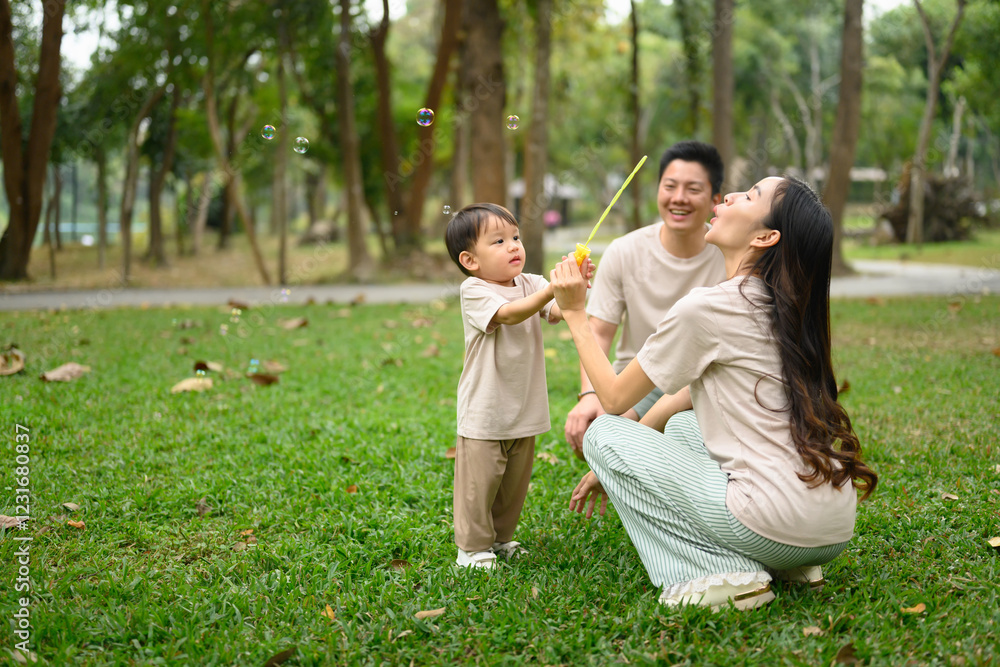 Little boy having playing with bubble with his parents in a lush green park Little boy having playing with bubble with his parents in a lush green park