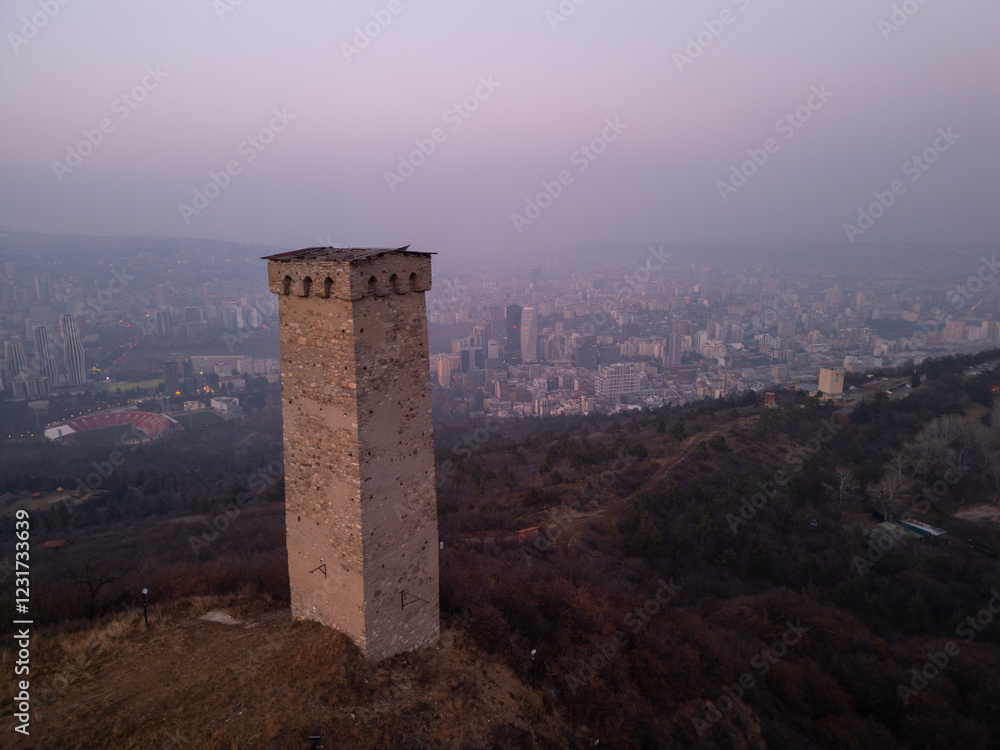 Ancient Georgian tower against the backdrop of modern Tbilisi city at dusk. Ancient Georgian tower against the backdrop of modern Tbilisi city at dusk.