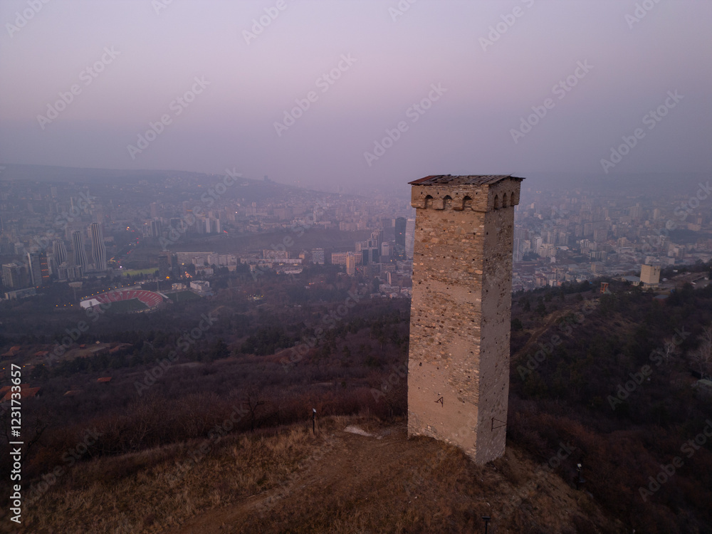 Ancient tower opposite city skyscrapers in Georgia - aerial view Ancient tower opposite city skyscrapers in Georgia - aerial view